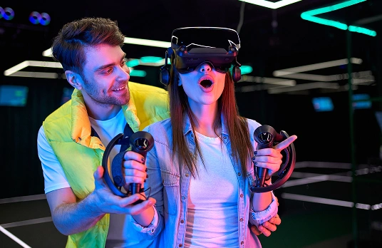 Op de foto zijn een jongen en een meisje te zien die in een club een virtual reality-spel spelen