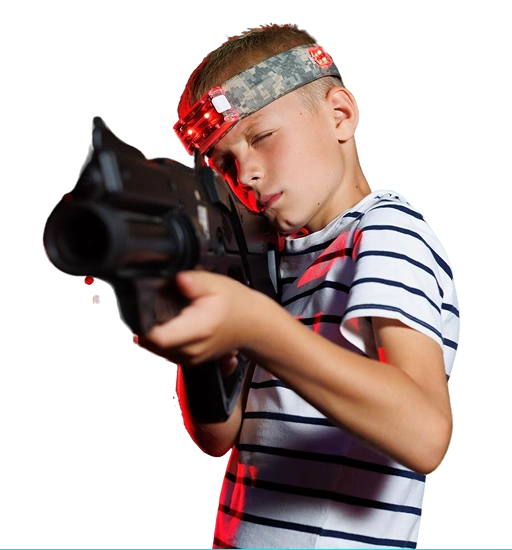 Een jongetje met een hoofdband met rode lampjes is vol aandacht gericht op een schietspel, tegen de achtergrond van een effen witte muur.